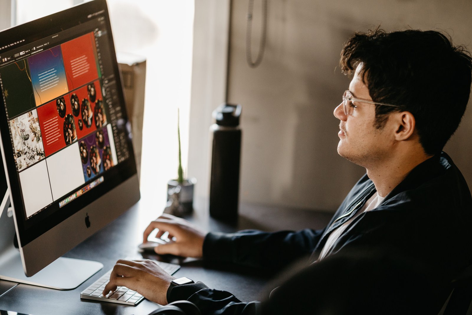 Designer analisando telas com elementos de design gráfico e paleta de cores em um computador
